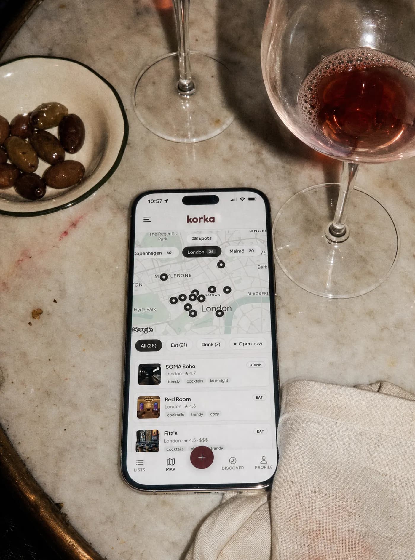 En telefon på ett marmorbord som visar Korkas karta över London med 28 sparade ställen