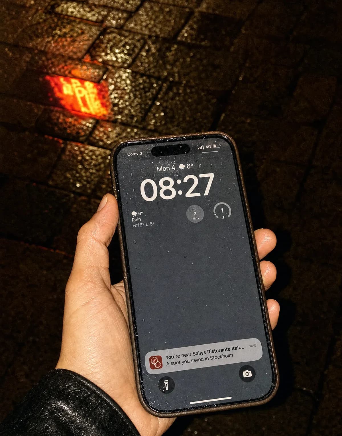 En telefon på en regnig gata på natten som visar en Korka-notis om ett sparat ställe i närheten